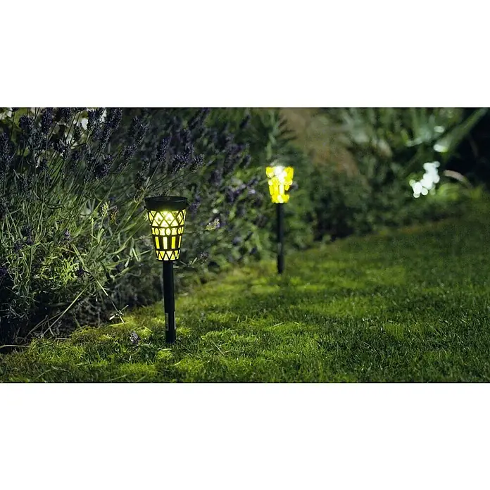 BAUHAUS Solar-Erdspieß - Schwarz/Gold, IP44, 3 lm - Zwei dekorative Solarleuchten beleuchten einen Gartenweg mit sanftem, warmem Licht, umgeben von üppigem Grün und Lavendelbüschen.