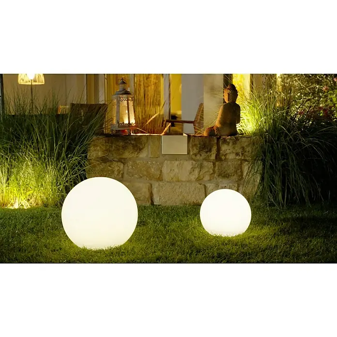 LED-Solar-DekoleuchteWeiß, 40 x 38 cm - Zwei leuchtende Kugellampen im Garten mit dekorativer Steinmauer, Laterne und Buddha-Statue im Hintergrund. Schafft eine gemütliche Atmosphäre.