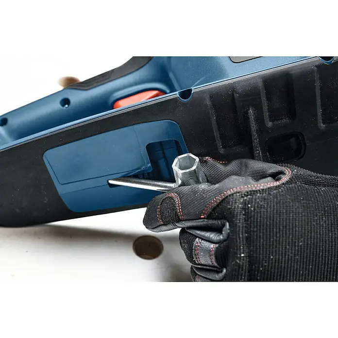 Bosch Professional AMPShare 18V Akku-Kettensäge GKE 18V-40 - 18 V, Li-Ionen, Ohne Akku, Schwertlänge: 40 cm - Ein Arbeiter mit Handschuhen justiert eine blaue Bosch-Elektrohobelmaschine mit einem Sechskantschlüssel. Präzision bei der Arbeit mit Werkzeugen.