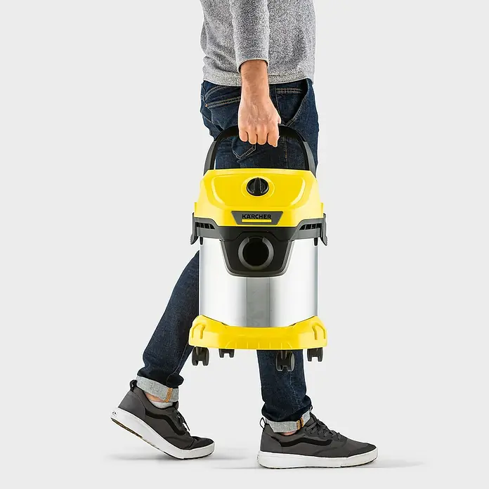Kärcher Elektro-Nass- & Trockensauger WD 3 S V-15/4/20 - 1.000 W, Behältervolumen: 15 l - Eine Person trägt einen gelb-silbernen Kärcher Mehrzwecksauger. Perfekt für Haus, Werkstatt und Auto!