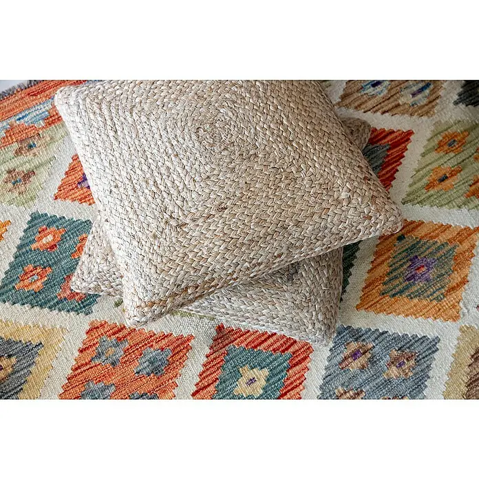 Alfombra de pelo corto Kilim Herat - Multicolor, 180 x 120 cm, 100% lana - Dos cojines cuadrados de yute beige apilados sobre una alfombra decorativa con patrones geométricos de colores. ¡Elegancia rústica para tu hogar!
