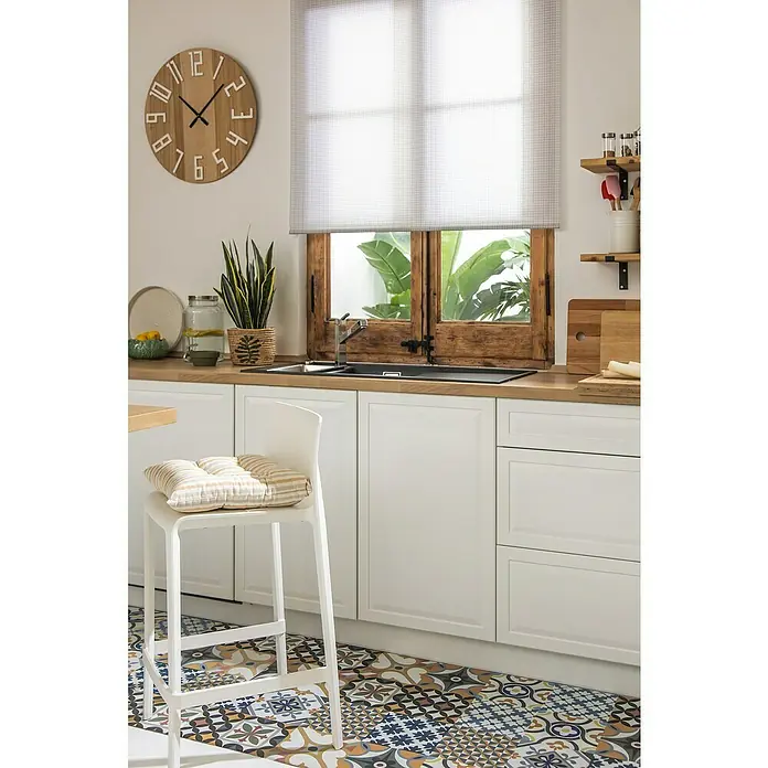 Versa Reloj de pared Madera - Diámetro: 60 cm, Marrón claro - Vista de una cocina con un llamativo suelo estampado y un taburete de bar blanco con un cojín de rayas. Contraventanas rústicas y un reloj de madera complementan el interior.