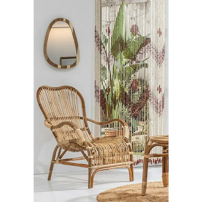 Espejo de pared Irregular Leca - 40 x 50 cm, Marrón - La imagen muestra un sillón de mimbre de ratán con reposabrazos delante de una pared con un espejo y una cortina de cuentas.