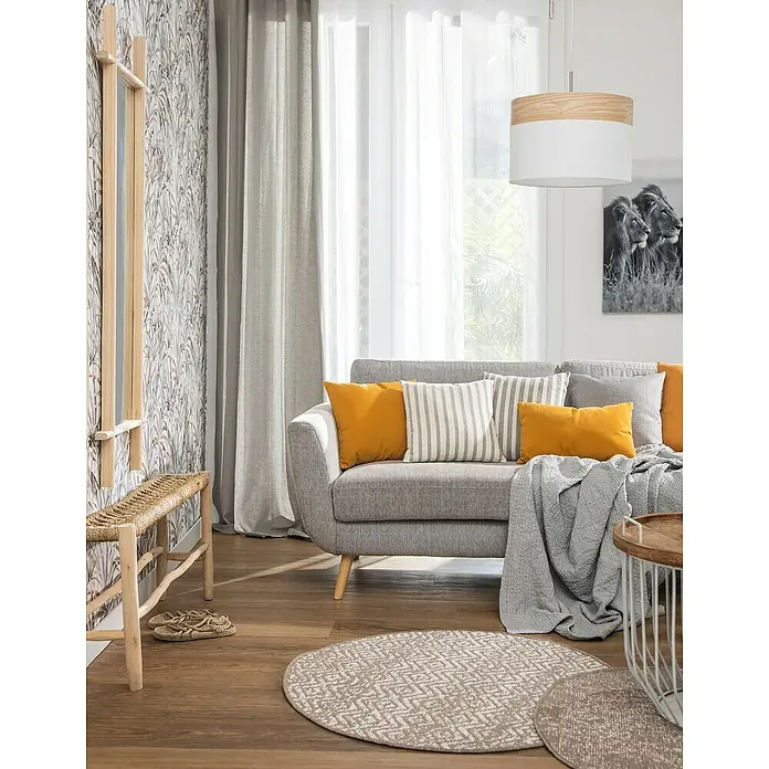 Papel pintado Vegetal con Hojas - Granate, Motivo decorativo, 10 x 0,53 m - Salón con sofá gris, cojines amarillos, alfombra redonda y taburete de madera. La pared está decorada con papel pintado estampado.