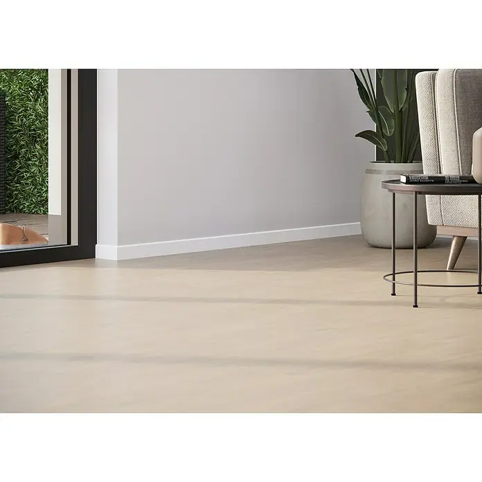 Sockelleiste - 244 x 0,95 x 5,8 cm, MDF - Eine Nahaufnahme eines Innenraums mit beigem Bodenbelag, einer weißen Fußleiste und einem modernen Beistelltisch. Zimmerpflanzen und ein Sessel ergänzen das Design.