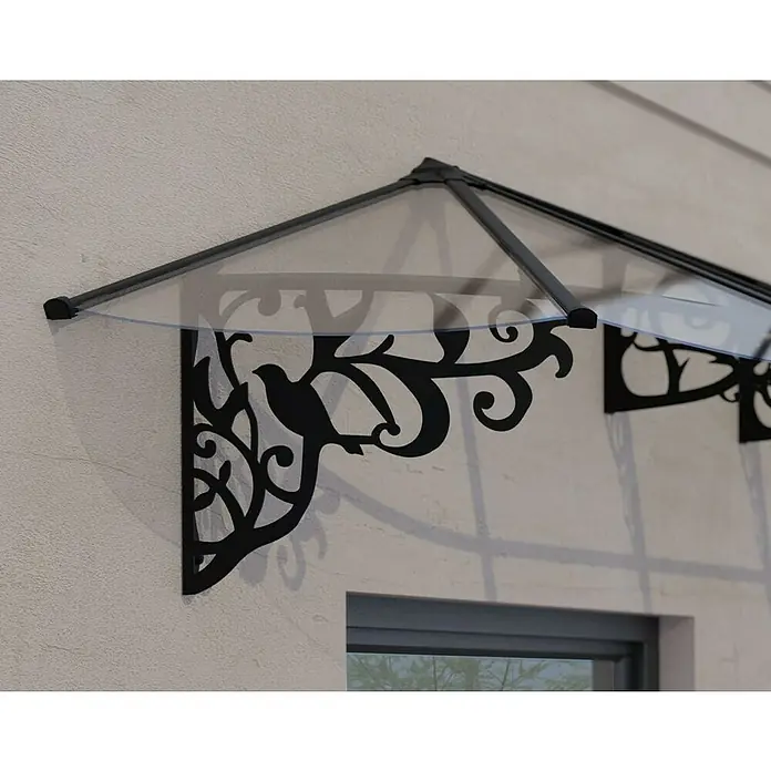 Palram – Canopia Marquesina para puerta Lily - 216 x 88 x 70 cm, Antracita - Primer plano de un toldo con motivo de pájaro y paneles transparentes, montado en una pared, que proyecta sombras sobre las ventanas.