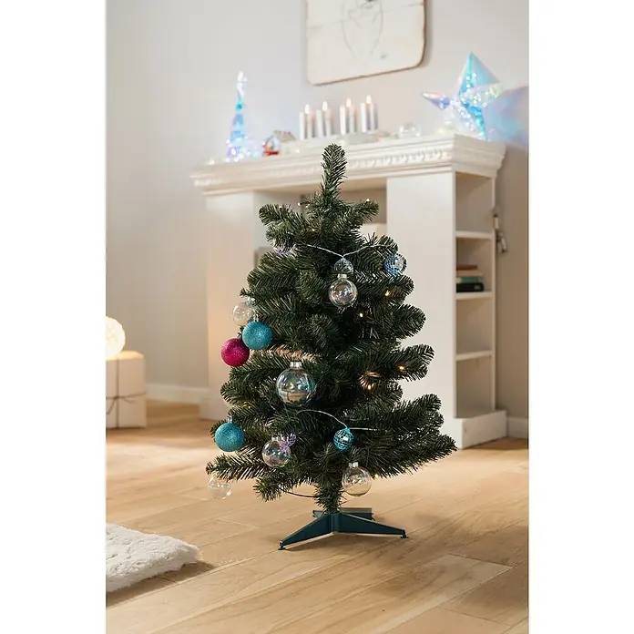 Künstlicher Weihnachtsbaum Allison - Höhe: 60 cm, Grün, LED-Beleuchtung - Dekorierten Tannenbaum mit blauen, pinken und transparenten Kugeln und silberfarbener Lichterkette auf einem Holzboden.