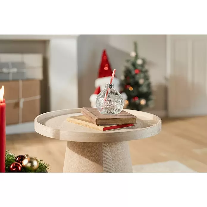 Trinkglas Partybecher Julia - Glas, Rot/Transparent - Ein klarer Trinkbecher in Form einer Christbaumkugel mit rot-weißem Strohhalm, auf Büchern auf einem hellen Holztisch inmitten von Weihnachtsdekorationen.