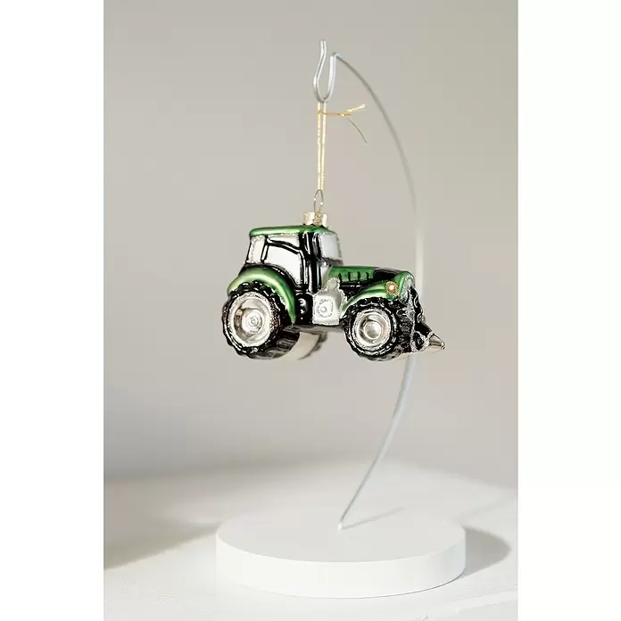 Christbaumschmuck Traktor - Grün, Glas, 1 Stk., 10 x 5,2 x 7,2 cm - Grün-schwarzer Traktor-Weihnachtsschmuck mit silbernen Details und Glitzerakzenten, an einem weißen Ständer hängend.