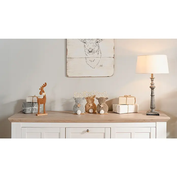 Dekofigur Hirsch - L x B x H: 13 x 5 x 24,5 cm, Braun/Grau, Holz, 1 Stk. - Dekorative Szene mit Elch-Kunstwerk, Stofftier-Rentieren, Geschenken und einer Lampe auf einem Schrank.