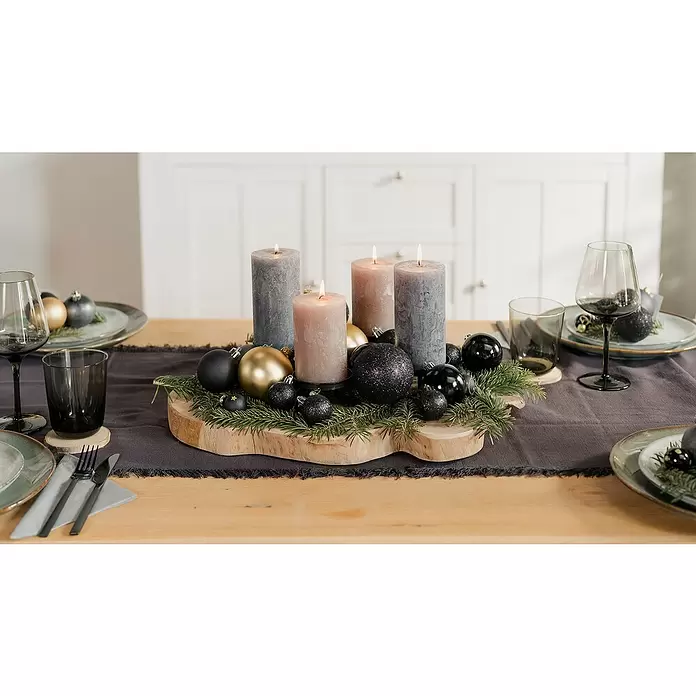 Adventskranz Holz - Durchmesser: 55 cm, Holz, Braun - Festliches Adventgesteck aus Holz mit brennenden grau/rosa Kerzen, schwarzen/goldenen Kugeln und Tanne, auf einem Tisch.