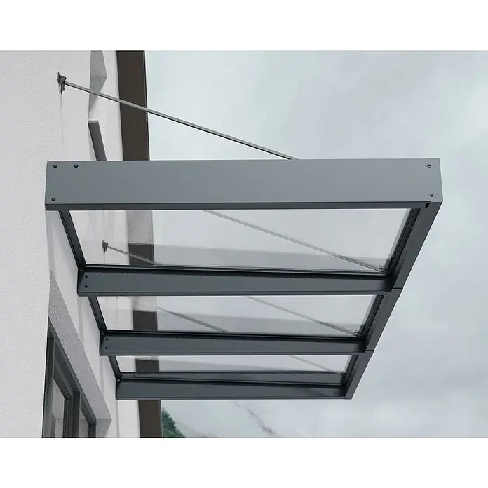 Palram – Canopia Marquesina para puerta Sophia XL - 286 x 140 x 17 cm, Gris antracita, Color del techo: Claro - Primer plano de un elegante toldo de vidrio con marcos metálicos grises, sujeto a un edificio, que muestra un diseño moderno.