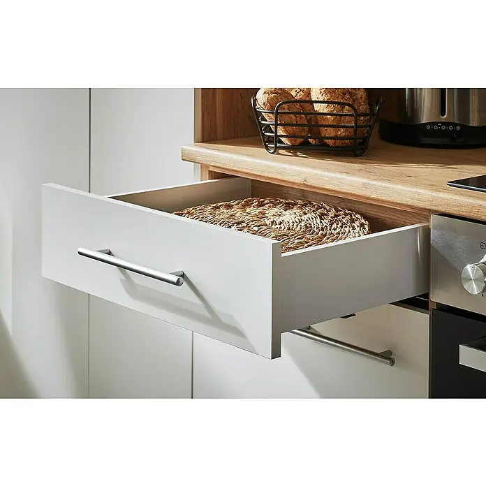 Respekta Inselküche Hilde Typ 1 - Breite: 310 cm, Weiß, Matt, Mit Elektrogeräten - Ein offener Küchenschrank mit einem gewebten Tischset darin, neben einer Arbeitsplatte mit Brot, Toaster und Backofen.