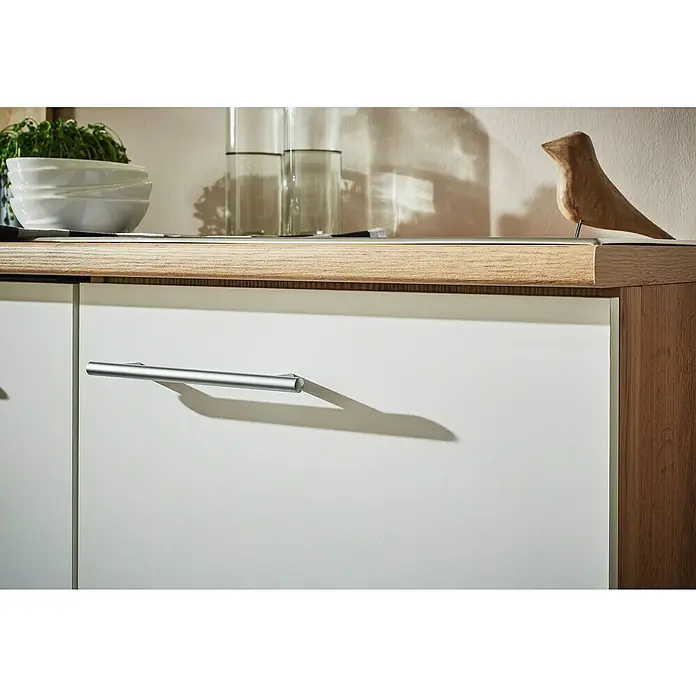 Respekta Inselküche Hilde Typ 1 - Breite: 310 cm, Weiß, Matt, Mit Elektrogeräten - Nahaufnahme eines modernen Sideboards mit weißen Fronten und silbernen Griffen. Das Möbelstück besticht durch sein schlichtes, elegantes Design.