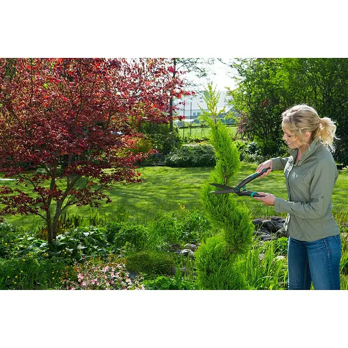 Gardena Hand-Heckenschere PrecisionCut - Länge: 475 mm - Eine Frau formt eine Pflanze mit einer Gardena Strauchschere im Garten. Die Schere ist ideal für präzise Schnitte und einfache Handhabung.