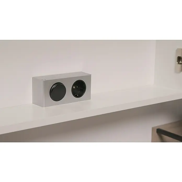 Riva LED-Spiegelschrank Luciana - B x H: 72 x 69,6 cm, Holz, Weiß - Silberne Steckdosenleiste mit einem Schalter und einer Steckdose, die sich auf einem weißen Regal in einem Schrank befindet.