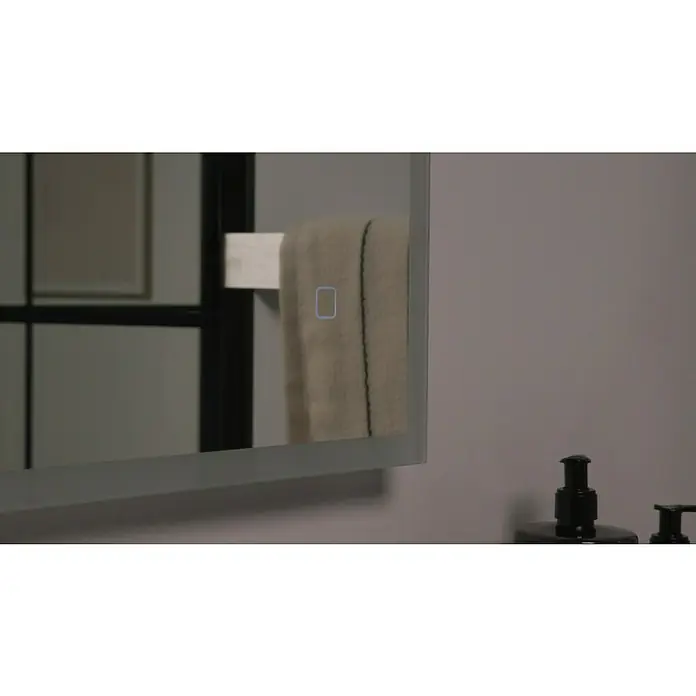 Riva LED-Lichtspiegel Draw Tape - 100 x 75 cm - Nahaufnahme eines Badezimmerspiegels mit Handtuchhalter, der ein Handtuch hält. Der Spiegel verfügt über einen integrierten Lichtschalter.