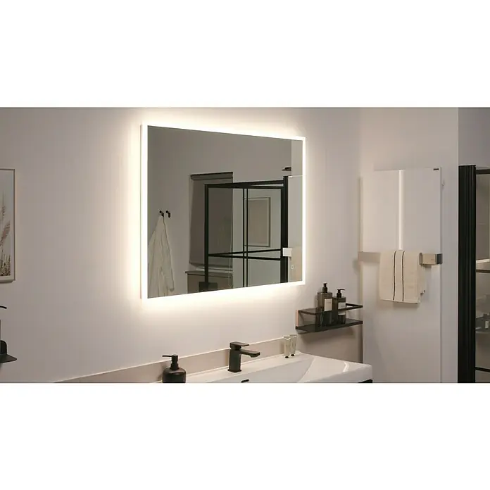 Riva LED-Lichtspiegel Draw Tape - 100 x 75 cm - Das Bild zeigt einen beleuchteten Badezimmerspiegel über einem Waschbecken mit Armatur und Ablage, neben einem Handtuchwärmer und einer Dusche.