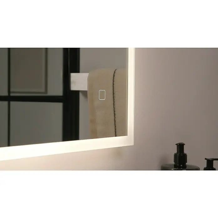 Riva LED-Lichtspiegel Draw Tape - 100 x 75 cm - Nahaufnahme eines beleuchteten Spiegels mit einem Handtuch im Hintergrund, der eine elegante Badezimmeratmosphäre ausstrahlt.