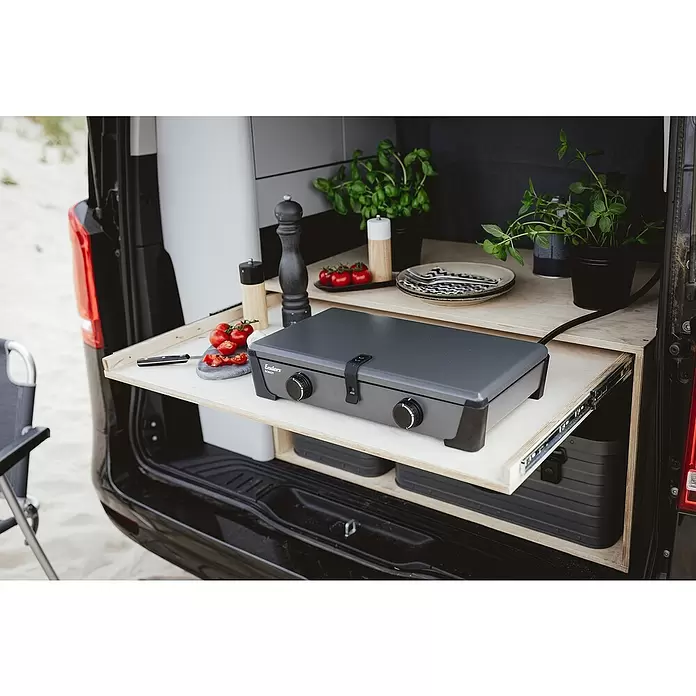 Enders Gaskocher Bondy 2 - 28 x 49 x 10 cm, 4,6 kW, Stahl - Grauer und schwarzer Enders Bondy Campingkocher auf einer ausziehbaren Holz-Kücheneinheit im Van, umgeben von Tomaten und Kräutern.