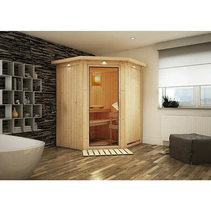 Karibu Elementsauna Larin - Ohne Ofen, Mit Dachkranz und Beleuchtung, L x B x H: 165 x 165 x 192 cm - Elegante Sauna aus hellem Holz mit Glaseingang und passender Holzmatte in einem stilvollen Badezimmer mit Steinwand.