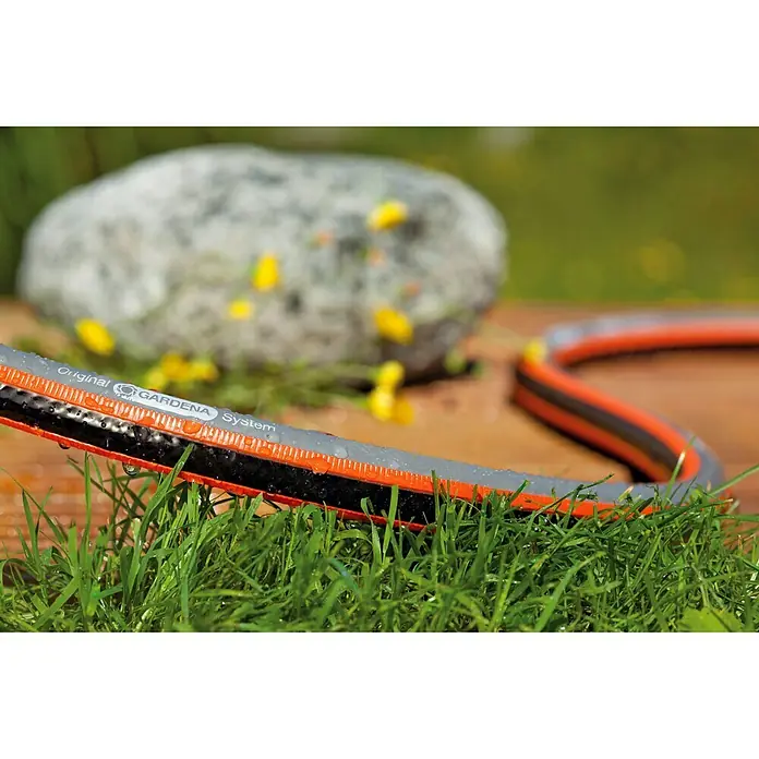 Gardena Comfort Schlauch-Set Flex - 20 m, Schlauchdurchmesser: 13 mm - Nahaufnahme eines mehrfarbigen Gardena-Gartenschlauchs mit "Original Gardena System"-Aufdruck, der auf grünem Gras und einer Holzoberfläche liegt.