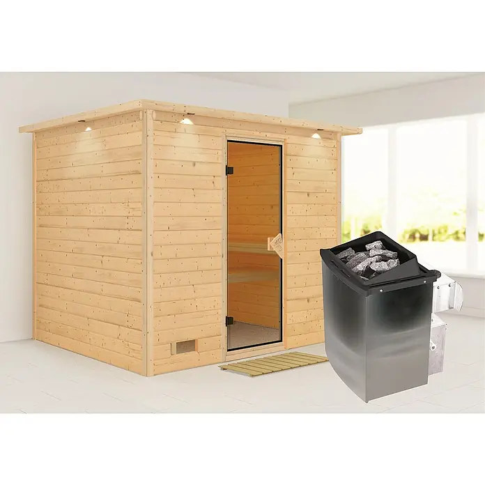 Karibu Massivholzsauna Sonara - Mit 9 kW Ofen mit integrierter Steuerung, Mit Dachkranz und Beleuchtung, L x B x H: 259 x 210 x 192 cm - Das Bild zeigt eine Sauna mit Holzverkleidung und einer Glastür, sowie einen Saunaofen mit Steinen. Die Sauna steht in einem hellen Raum.