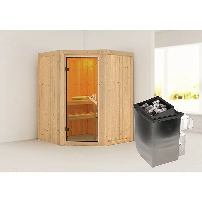 Karibu Elementsauna Larin - Mit 9 kW Ofen mit integrierter Steuerung, Ohne Dachkranz, L x B x H: 151 x 151 x 192 cm - Eine helle Holzsauna mit Glastür und einem Saunaofen voller Steine steht in einem Raum mit hellen Wänden.