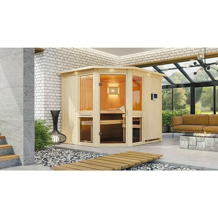 Karibu Elementsauna Amelia 3 - Mit 9 kW Ofen mit externer Steuerung, Mit Dachkranz und Beleuchtung, L x B x H: 245 x 210 x 192 cm - Die Abbildung zeigt eine moderne Holzsauna mit Glasfront in einem stilvollen Innenraum, der zum Entspannen einlädt.