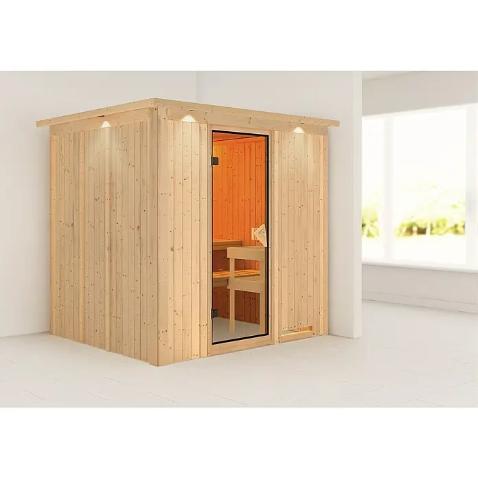 Karibu Elementsauna Sodin - Ohne Ofen, Mit Dachkranz und Beleuchtung, L x B x H: 210 x 184 x 192 cm - Eine helle Holzsauna mit Glastür und Beleuchtung steht in einem hellen Raum mit Fliesenboden.