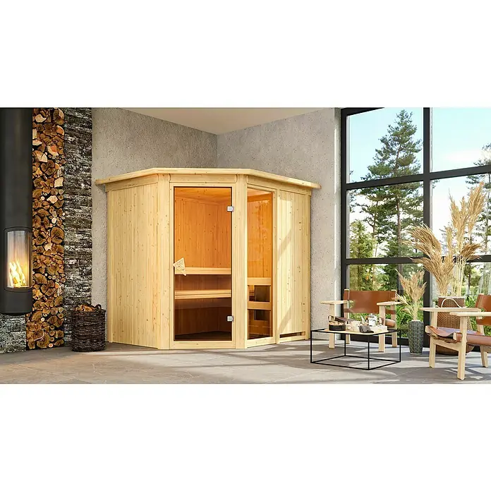 Karibu Elementsauna Fiona - Ohne Ofen, Mit Dachkranz und Beleuchtung, L x B x H: 210 x 184 x 192 cm - Eine stilvolle Ecke des Hauses mit einer Sauna aus hellem Holz, einem Kamin und natürlichen Elementen.