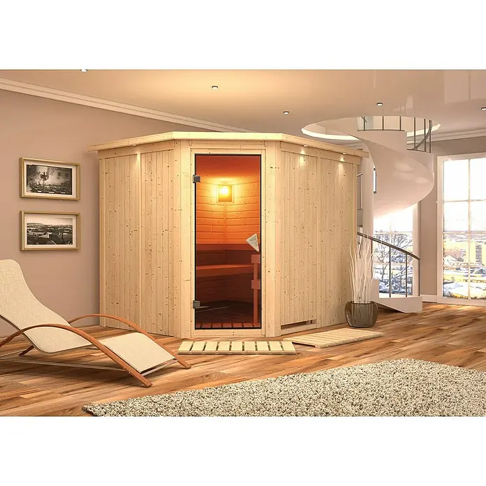 Karibu Elementsauna Malin - Mit 9 kW Ofen mit integrierter Steuerung, Mit Dachkranz und Beleuchtung, L x B x H: 245 x 210 x 192 cm - Elegante Saunakabine aus Holz mit Glastür und Inneneinrichtung, ergänzt durch Liegestuhl und Dekoration in einem stilvollen Raum.