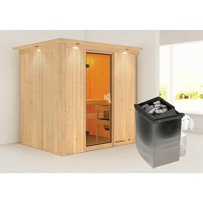 Karibu Elementsauna Bodin - Mit 9 kW Ofen mit integrierter Steuerung, Mit Dachkranz und Beleuchtung, L x B x H: 210 x 165 x 192 cm - Saunabild mit klarem Fokus auf die Sauna und den Saunaofen. Die Sauna ist aus hellem Holz gefertigt, der Saunaofen ist mit Steinen gefüllt.