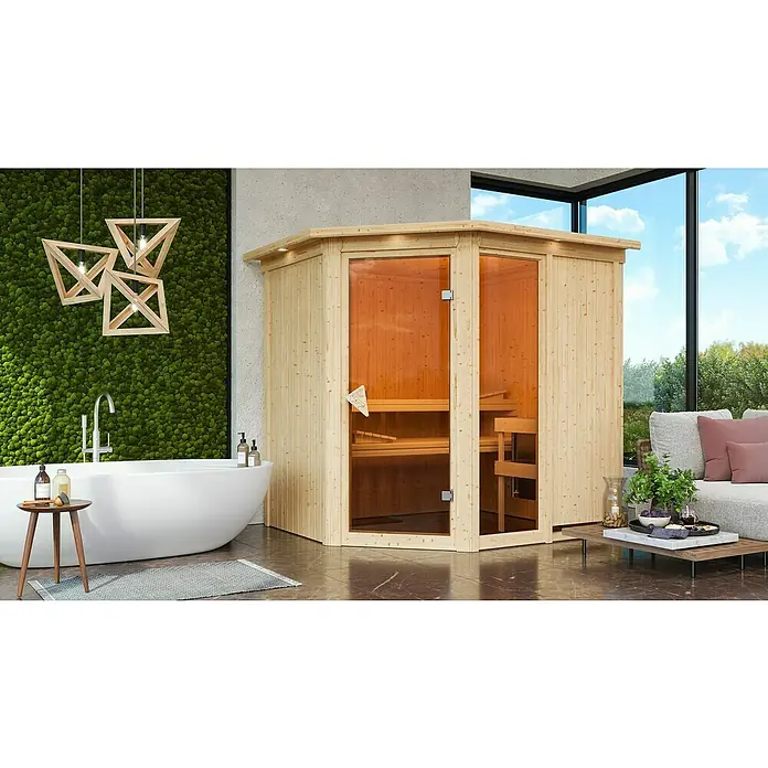Karibu Elementsauna Fiona - Mit 9 kW Ofen mit integrierter Steuerung, Mit Dachkranz und Beleuchtung, L x B x H: 210 x 184 x 192 cm - Die Ecksauna aus hellem Holz mit Glasfront bietet Platz zum Entspannen. Sie steht in einem modernen Badezimmer mit Badewanne und Sitzgelegenheit.