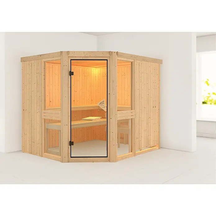 Karibu Elementsauna Amelia 3 - Ohne Ofen, Ohne Dachkranz, L x B x H: 231 x 196 x 192 cm - Ein Ecksauna-Modell aus hellem Holz mit gläserner Tür, das in einem hellen Raum steht. Ideal für Wellness zu Hause.