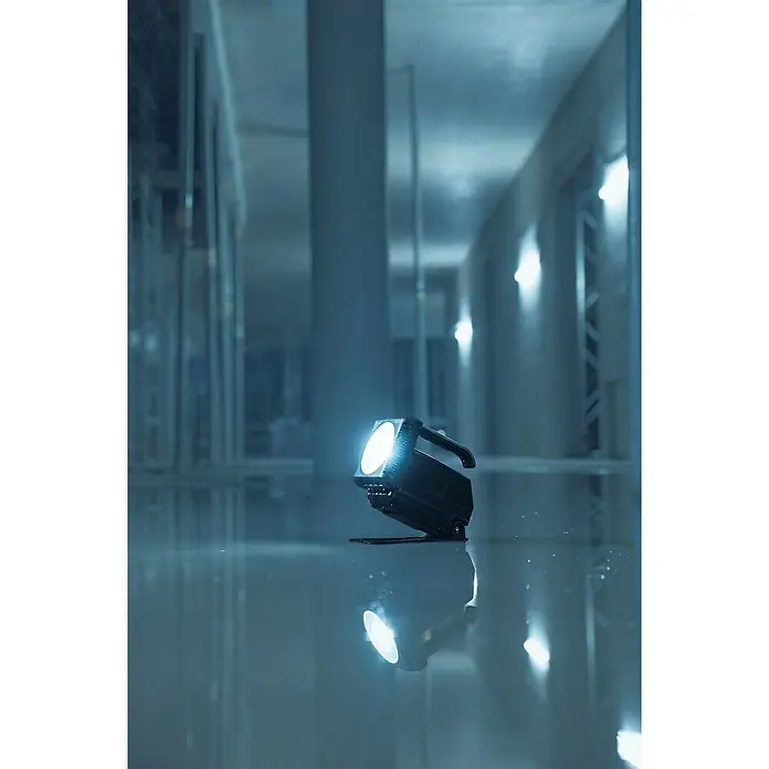 Brennenstuhl Taschenlampe Multi Akku - 21,4 x 22,5 x 19,5 cm - Das Bild zeigt einen tragbaren LED-Arbeitsstrahler, der ein helles, fokussiertes Licht in einer kühlen, bläulichen Umgebung ausstrahlt. Das Licht spiegelt sich auf dem Boden.