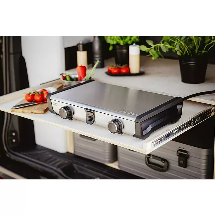 Enders Gaskocher Ryda 2Z - L x B x H: 32 x 52 x 9,5 cm, Edelstahl, 4,6 kW - Tragbarer Edelstahlkocher mit schwarzen Bedienelementen auf einer ausziehbaren Holzablage. Frische Zutaten in Wohnmobilküche daneben.