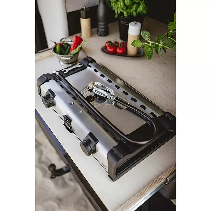 Enders Gaskocher Ryda 2Z - L x B x H: 32 x 52 x 9,5 cm, Edelstahl, 4,6 kW - Ein silberner tragbarer Gaskocher mit schwarzen Bedienelementen und Gasschlauch, bereit auf heller Holztheke mit frischen Zutaten.