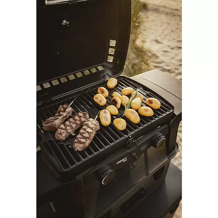 Enders Gasgrill Urban II - Grillfläche (B x T): 49 x 32 cm, 4,4 kW, Anzahl Brenner: 2 Stk. - Schwarzer Enders Urban II Pro Gasgrill mit Fleisch und Kartoffeln auf dem Rost, im Freien.
