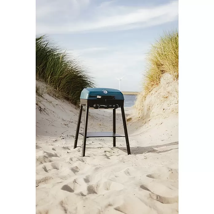 Enders Gasgrill Explorer II Pro Caravan - Grillfläche (B x T): 49 x 32 cm, 4,4 kW, Anzahl Brenner: 2 Stk., 30 mbar - Blauer und schwarzer tragbarer Grill auf einem Ständer am Sandstrand zwischen Dünen, ideal für Outdoor-Kochen.
