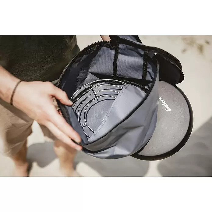 Enders Transporttasche Vamo - Passend für: Enders Backofenaufsatz Vamo, PVC - Person öffnet graue Tragetasche mit Metallgrillrosten und Enders Portabelgrilldeckel.