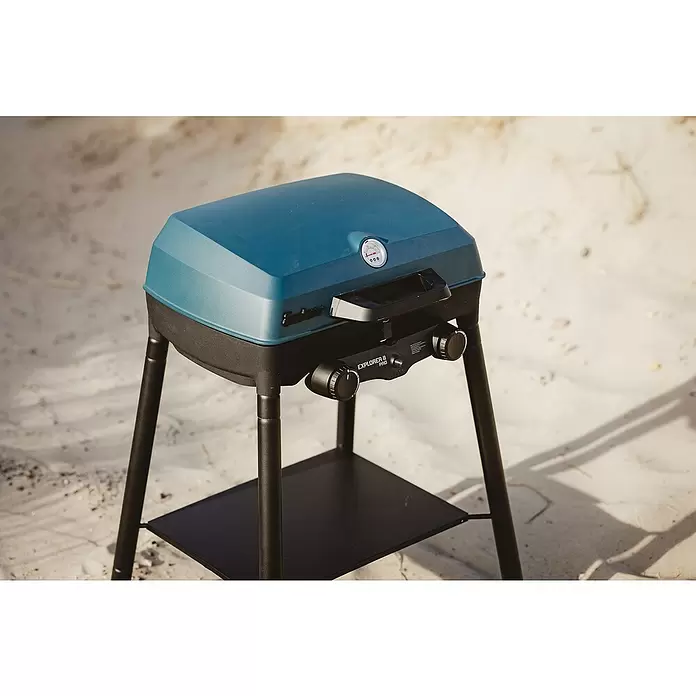 Enders Gasgrill Explorer II Pro Caravan - Grillfläche (B x T): 49 x 32 cm, 4,4 kW, Anzahl Brenner: 2 Stk., 30 mbar - Ein blauer und schwarzer tragbarer Gasgrill, Modell Explorer II Pro, auf einem schwarzen Ständer im Sand.