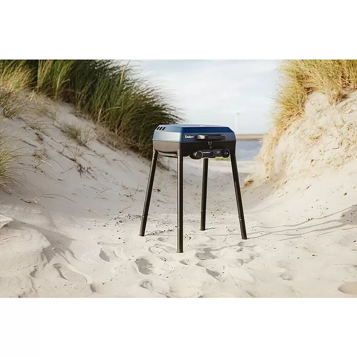 Enders Gasgrill Explorer II - Grillfläche (B x T): 49 x 32 cm, 4 kW, Anzahl Brenner: 2 Stk., 50 mbar - Blau-schwarzer Enders Explorer II Gasgrill auf langen Beinen, aufgebaut in Sanddünen mit Strandhafer.