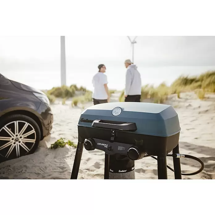 Enders Gasgrill Explorer II Pro - Grillfläche (B x T): 49 x 32 cm, 4,4 kW, Anzahl Brenner: 2 Stk., 50 mbar - Tragbarer dunkelgrün-schwarzer Enders Explorer II Pro Gasgrill mit Bedienknöpfen am Sandstrand.