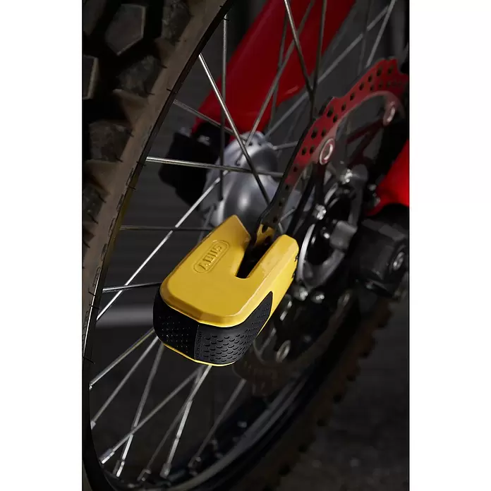Abus Bremsscheibenschloss GRANIT™ Detecto One 8078 2.0 - Geeignet für: Motorrad, Gelb - Gelbes Bremsscheibenschloss an der Vorderradbremse eines Motorrads, mit schwarzem Gummigriff, Reifen und Speichen.