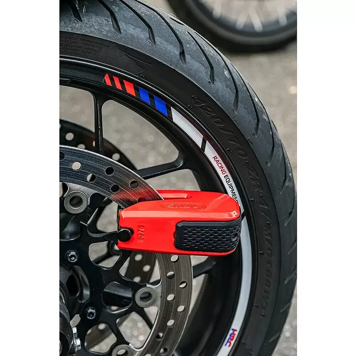 Abus Bremsscheibenschloss GRANIT™ Detecto One 8078 2.0 - Geeignet für: Motorrad, Rot - Rotes ABUS Bremsscheibenschloss an der Vorderradbremsscheibe eines Motorrads befestigt.