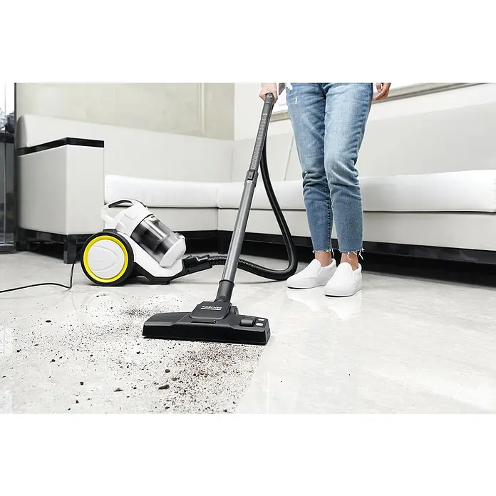 Kärcher Elektro-Staubsauger VC 3 - 700 W - Eine Person, die mit einem Kärcher Staubsauger eine verschmutzte Bodenfläche reinigt, wobei der Fokus auf dem Staubsauger liegt.