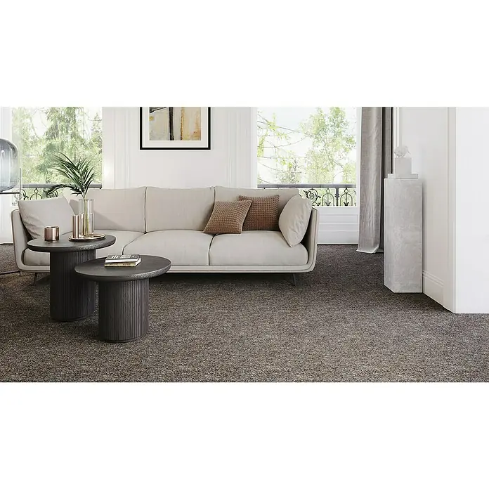 Teppichfliese Sprinter - Nadelfilz, 80 % Polypropylen, 20 % recyceltes PET, Schokobraun - Elegantes Wohnzimmer mit grauem Teppichboden, der dem Raum Wärme und Textur verleiht. Das Sofa und die Tische harmonieren perfekt mit dem Teppich.