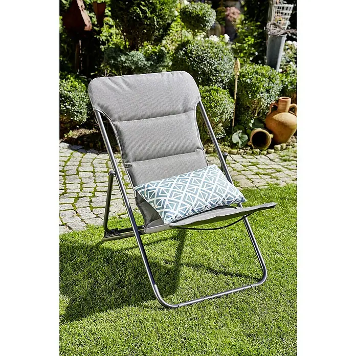 Sunfun Garten-Liegestuhl - Hellgrau, Klappbar - Bild einer grauen, klappbaren Gartenliege mit blau-weiß gemustertem Kissen auf grünem Rasen im Garten.