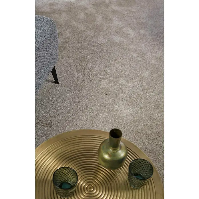 Teppichfliese Amazing - Hochflor, 100 % Polyester, Beige - Elegante Nahaufnahme eines Wohnzimmers mit einem Couchtisch aus Gold mit zwei Gläsern und einer Vase. Ein Teil eines Sessels ist im Hintergrund zu sehen.